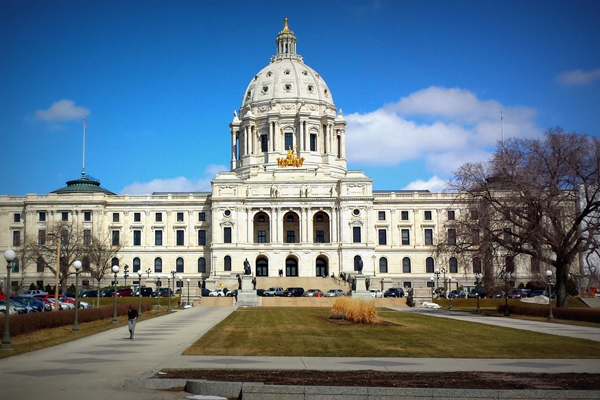 [ai] The exterior of a large, historic building with a prominent dome under a blue sky. The building features classical architecture with columns and large windows. In the foreground, a pathway leads through a landscaped area.